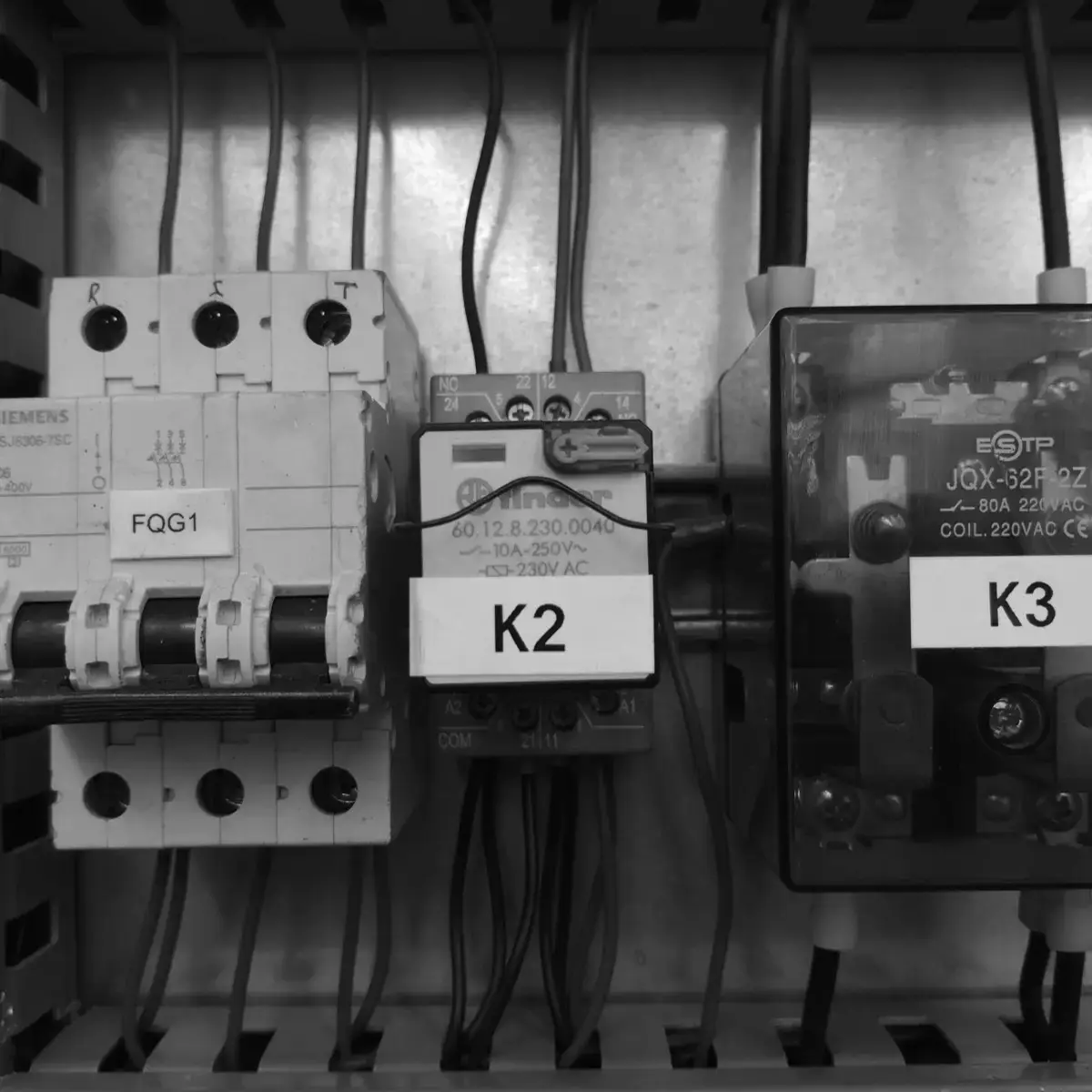 Control rail inside the cabinet: three-phase circuit breaker, power contactor and auxiliary relay, each with its identification label.